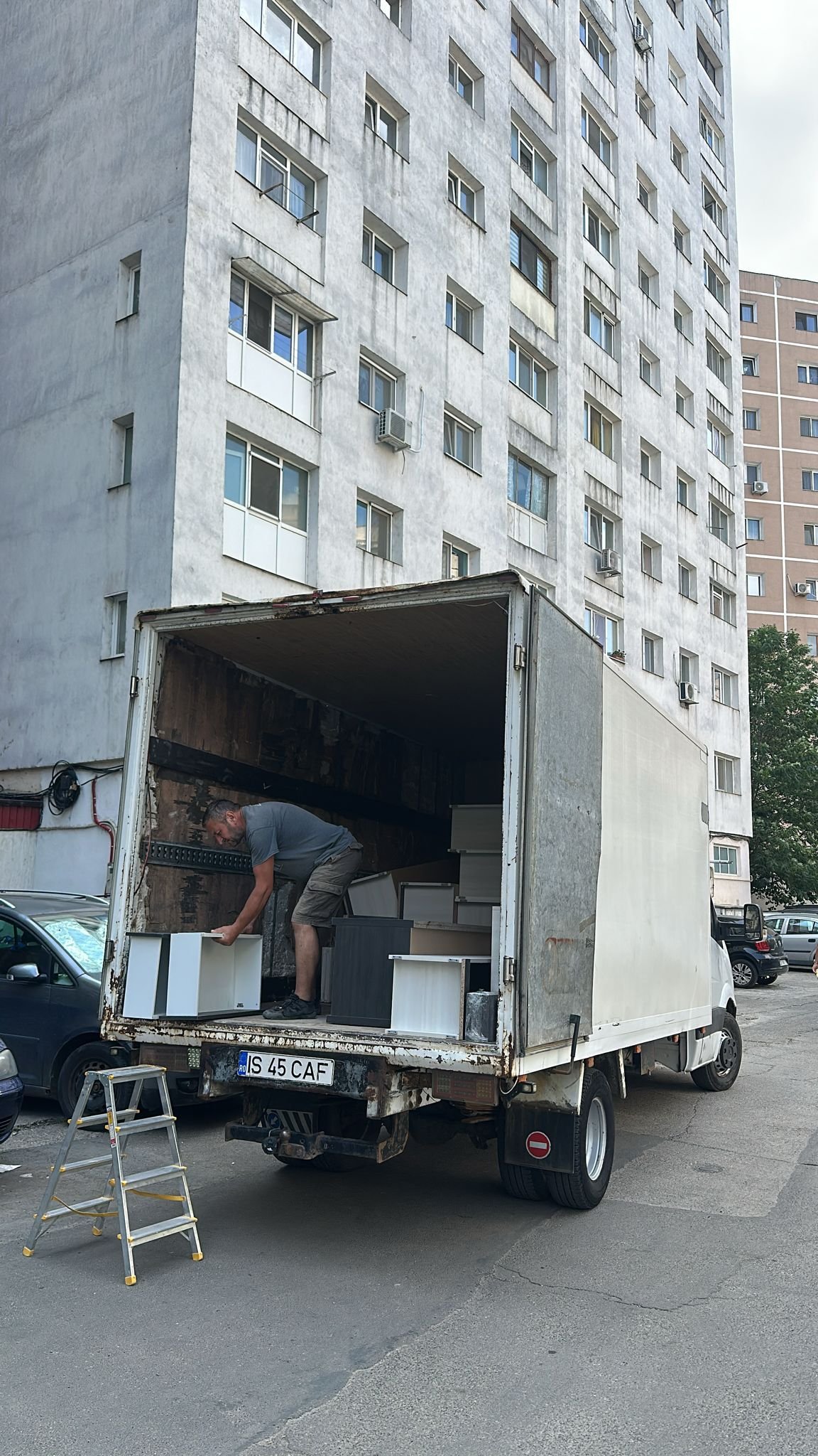 Muncitor aranjeaza corpuri de mobilier alb in camion la o mutare de bloc