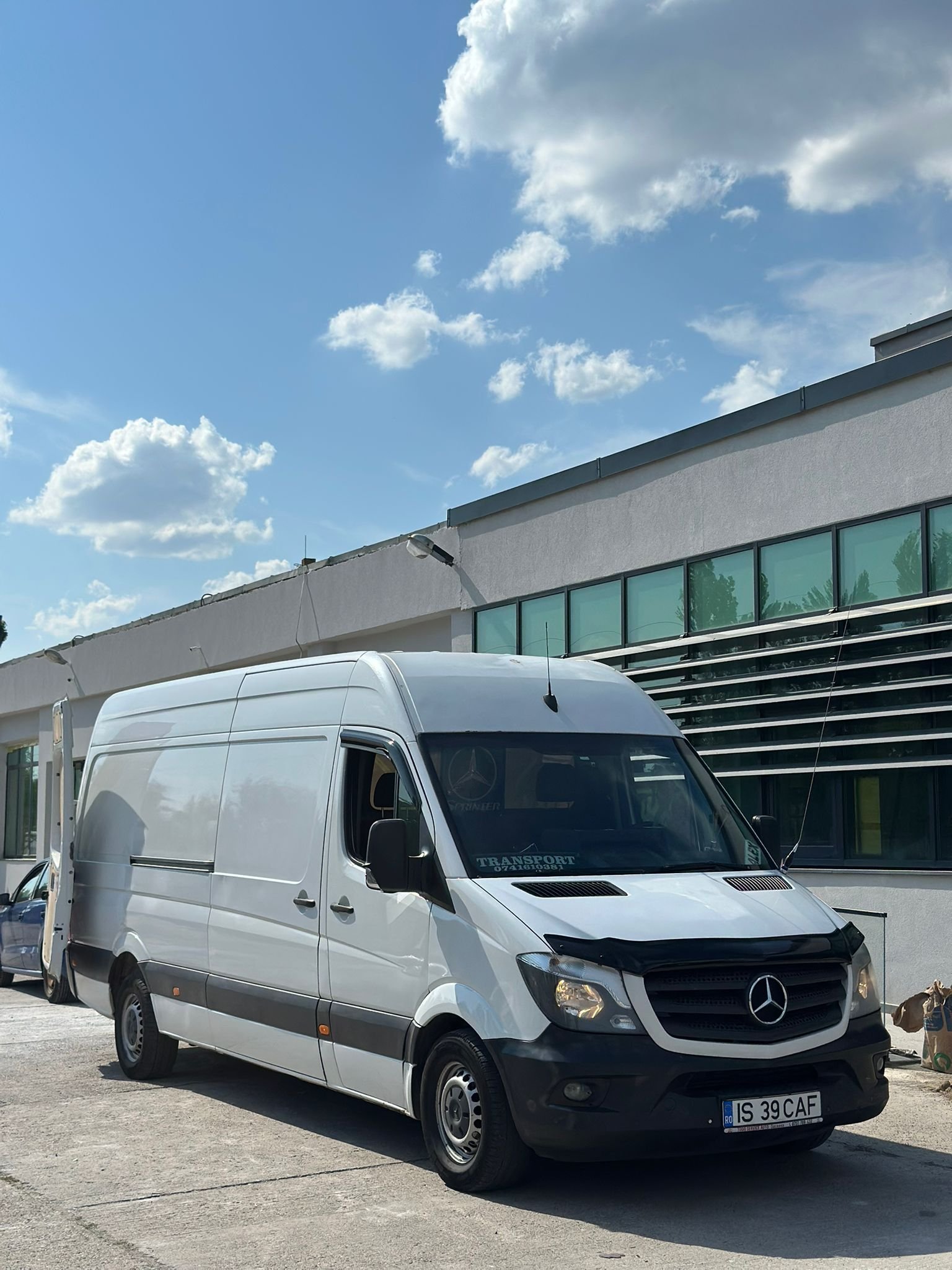 Duba Mercedes Sprinter alba parcata in fata unei hale industriale