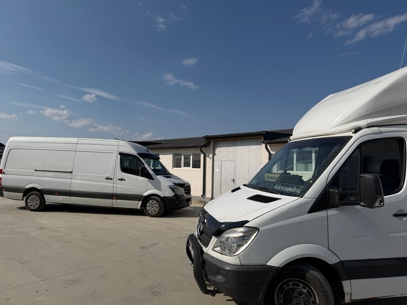 Doua dube Mercedes Sprinter albe parcate in fata sediului firmei de transport