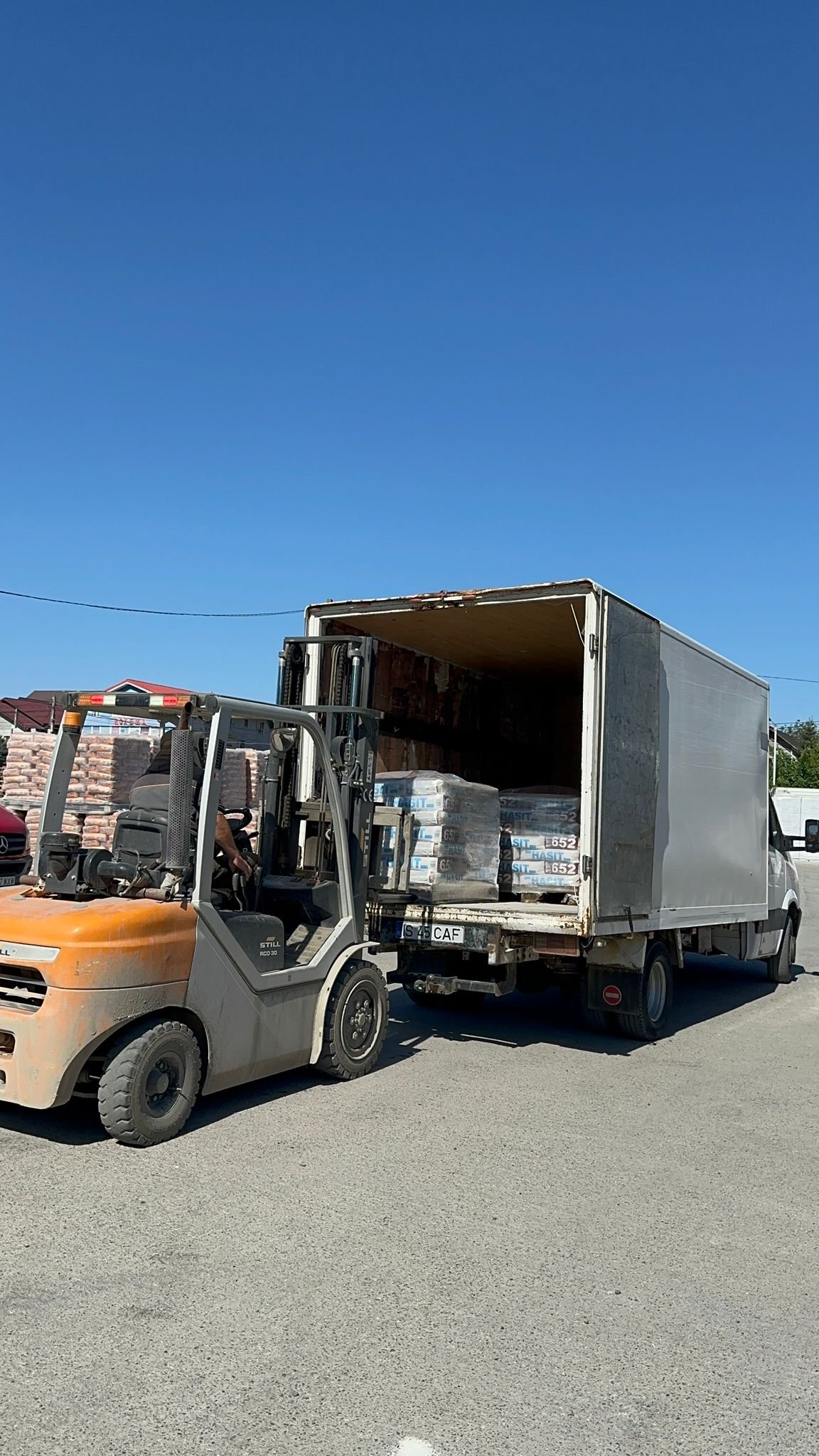 Motostivuitor incarca paleti cu saci de tencuiala in camionul cu cutie