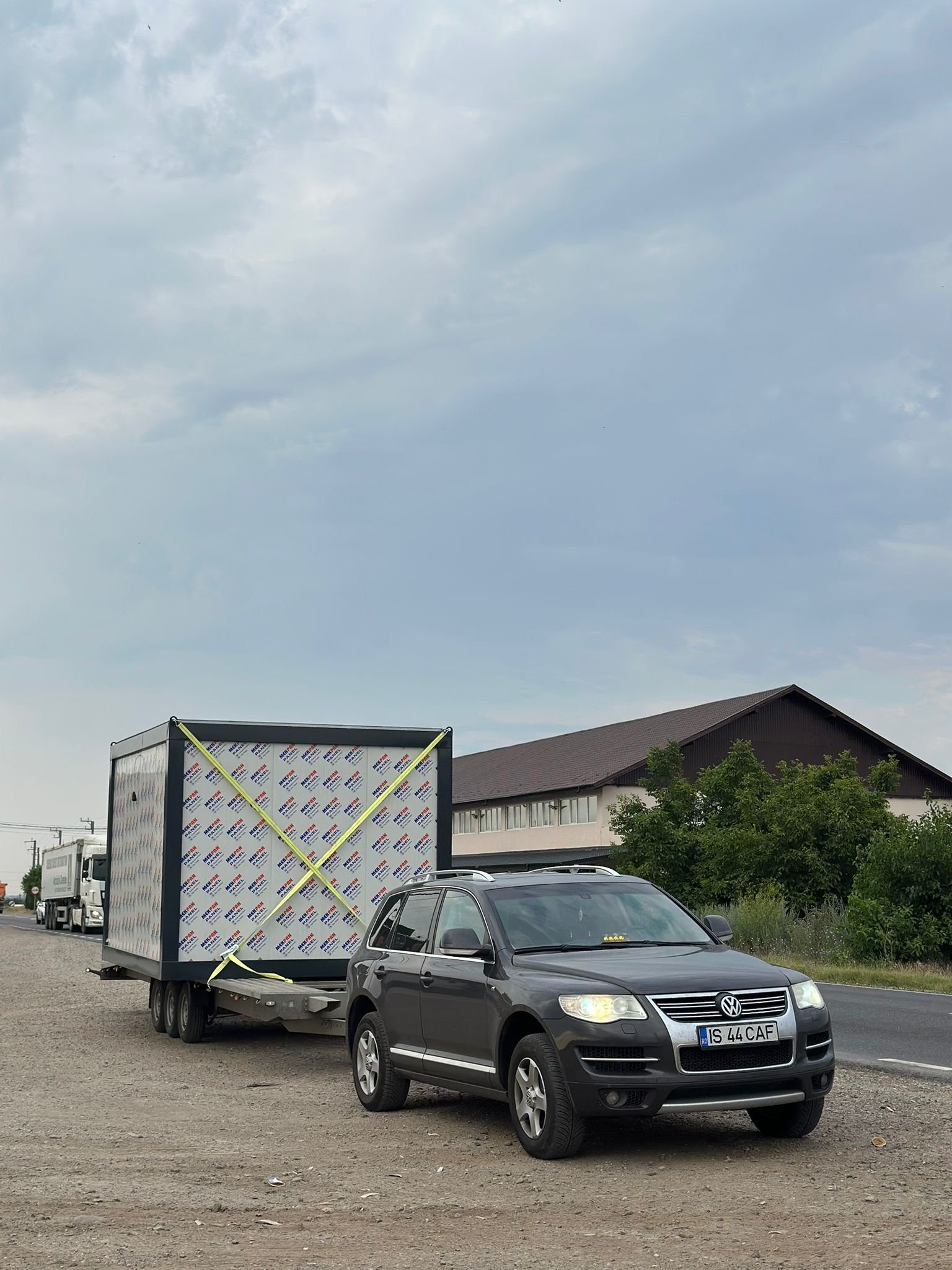 SUV Volkswagen Touareg tracteaza o cabina modulara ancorata cu chingi pe remorca